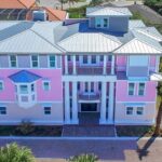 The Mallory three story home at Ponce Inlet Key, with bright pink exterior on upper levels and a rooftop viewing room to see the ocean and waterway on either side of the town.